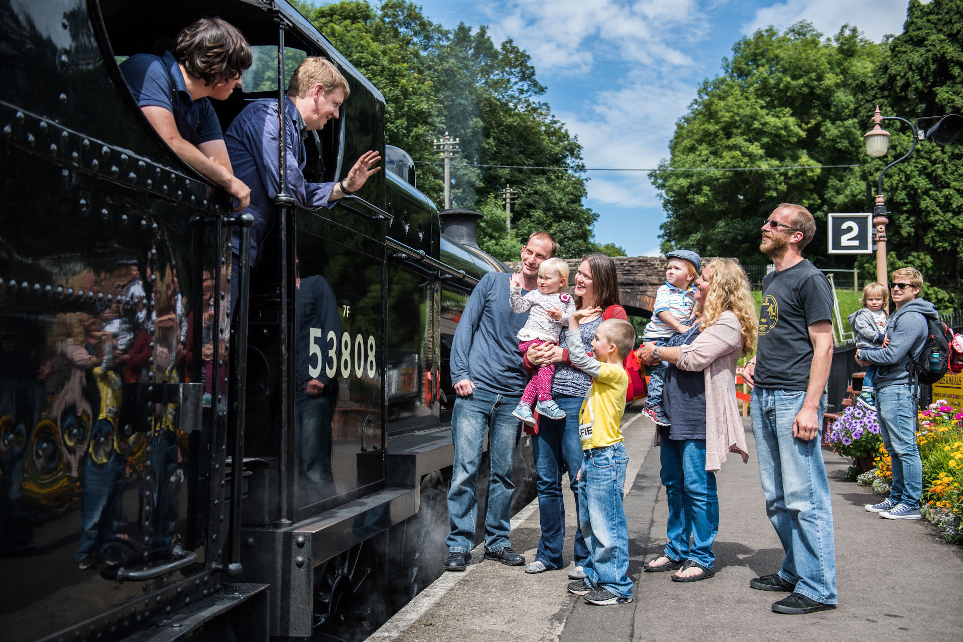 A family waves at the crew of a steam locomotive