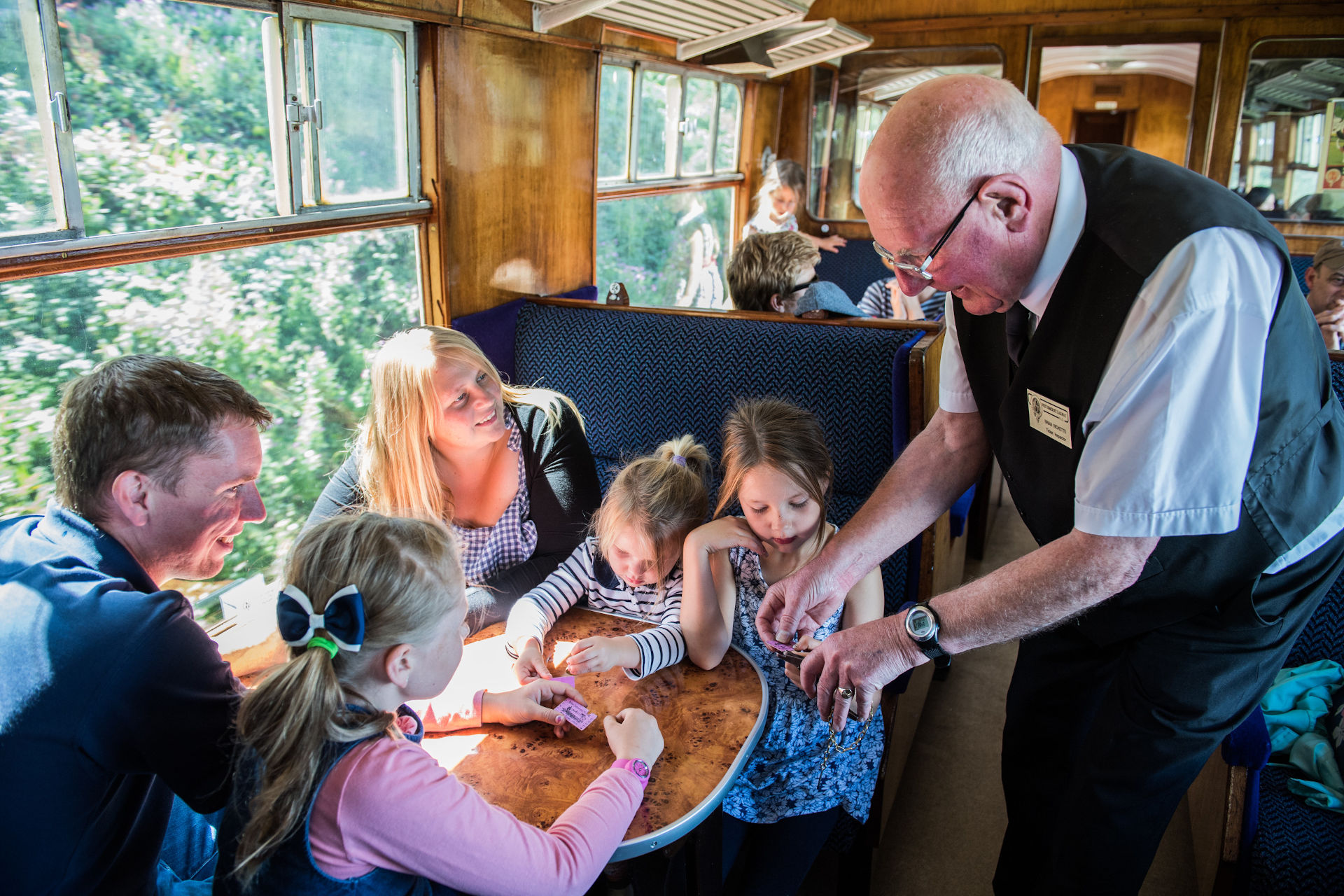 A young family smile at a ticket collector on a train